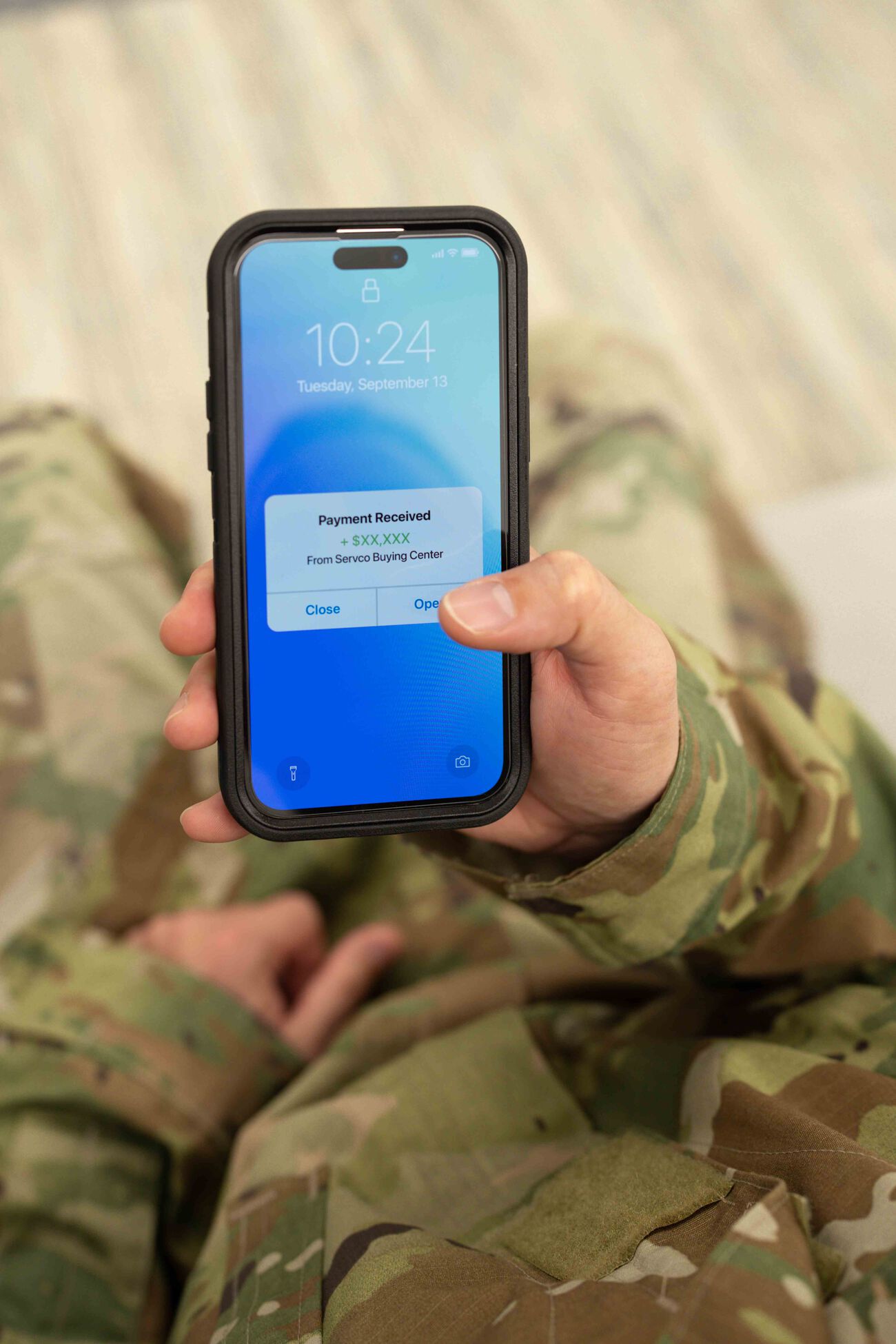 The military person receives a payment on their phone after selling their car.