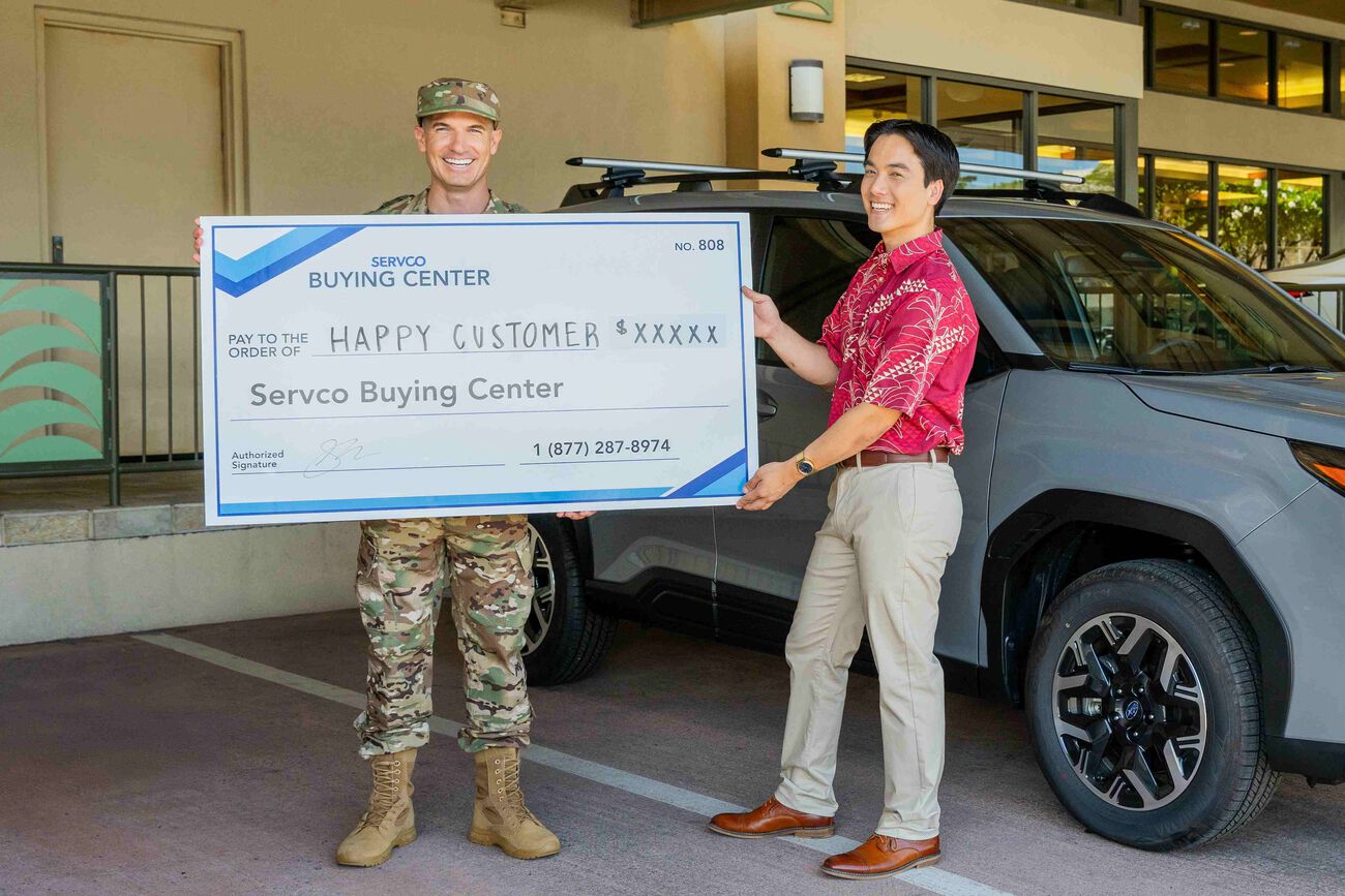 The customer and Servco Buying Center representative are holding the check, which is given to the customer after selling their car.