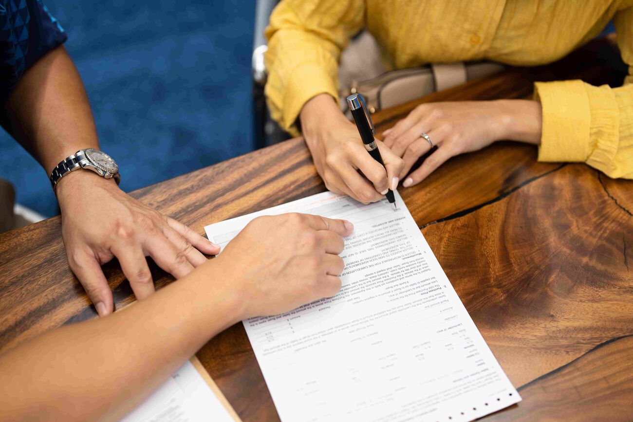 The mover and Servco Buying Center representative signs paperwork in preparation to sell the car.