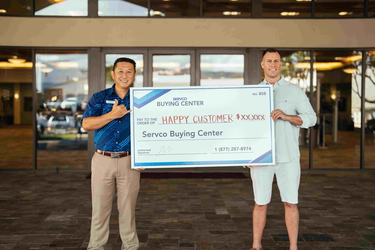 The customer and Servco Buying Center representative are holding the check, which is given to the customer after selling their car.