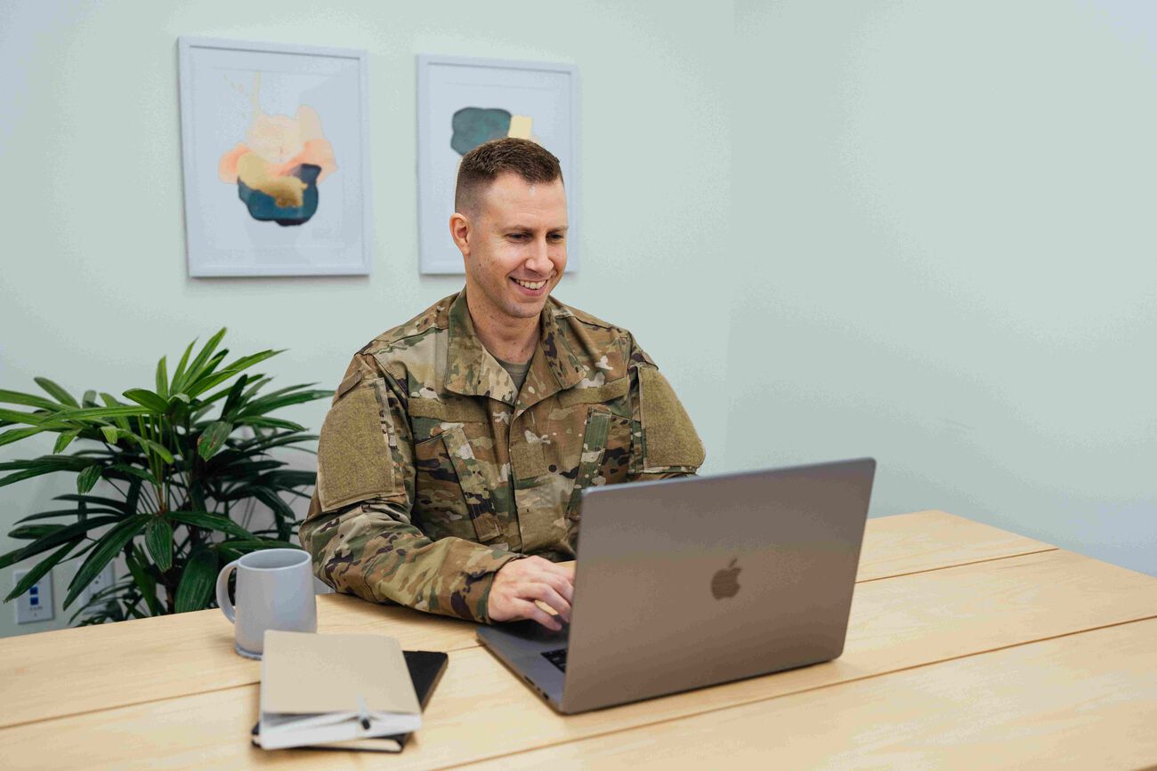 The military person is on the laptop, scrolling through the Servco Buying Center&rsquo;s website.